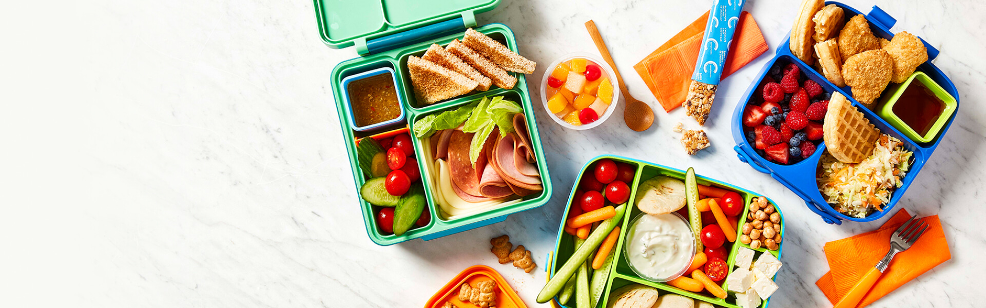 three bento lunch boxes filled with different kid's school lunches on a marble surface