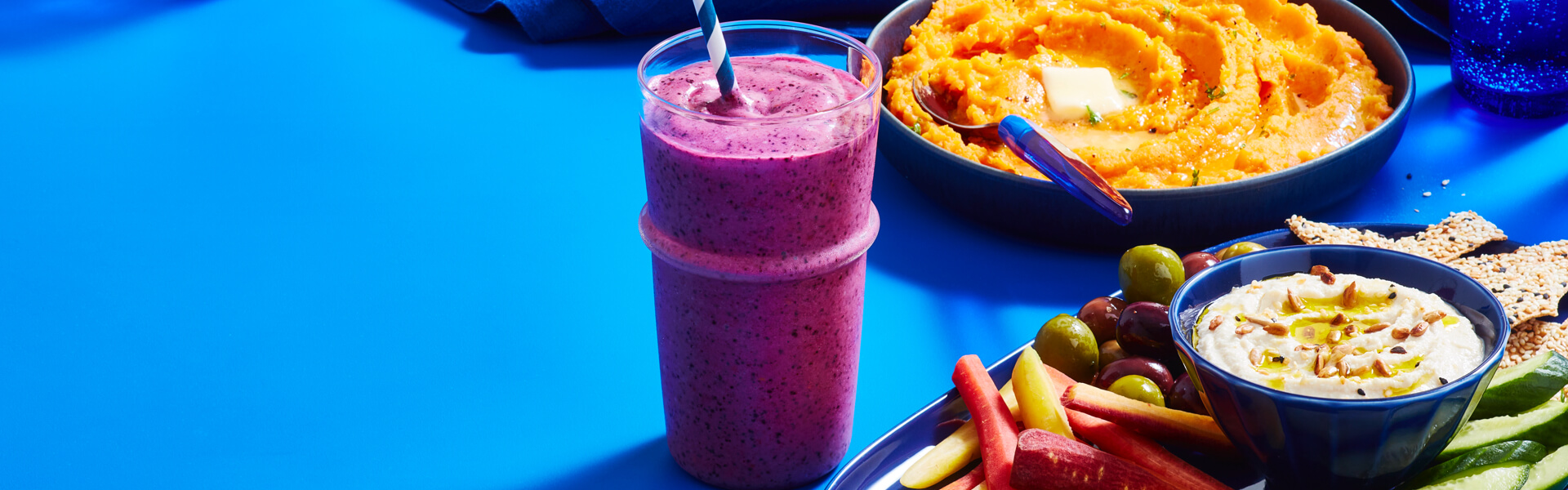 Cauliflower-fruit smoothie, cauliflower and sweet potato mash, and cauliflower hummus on blue table