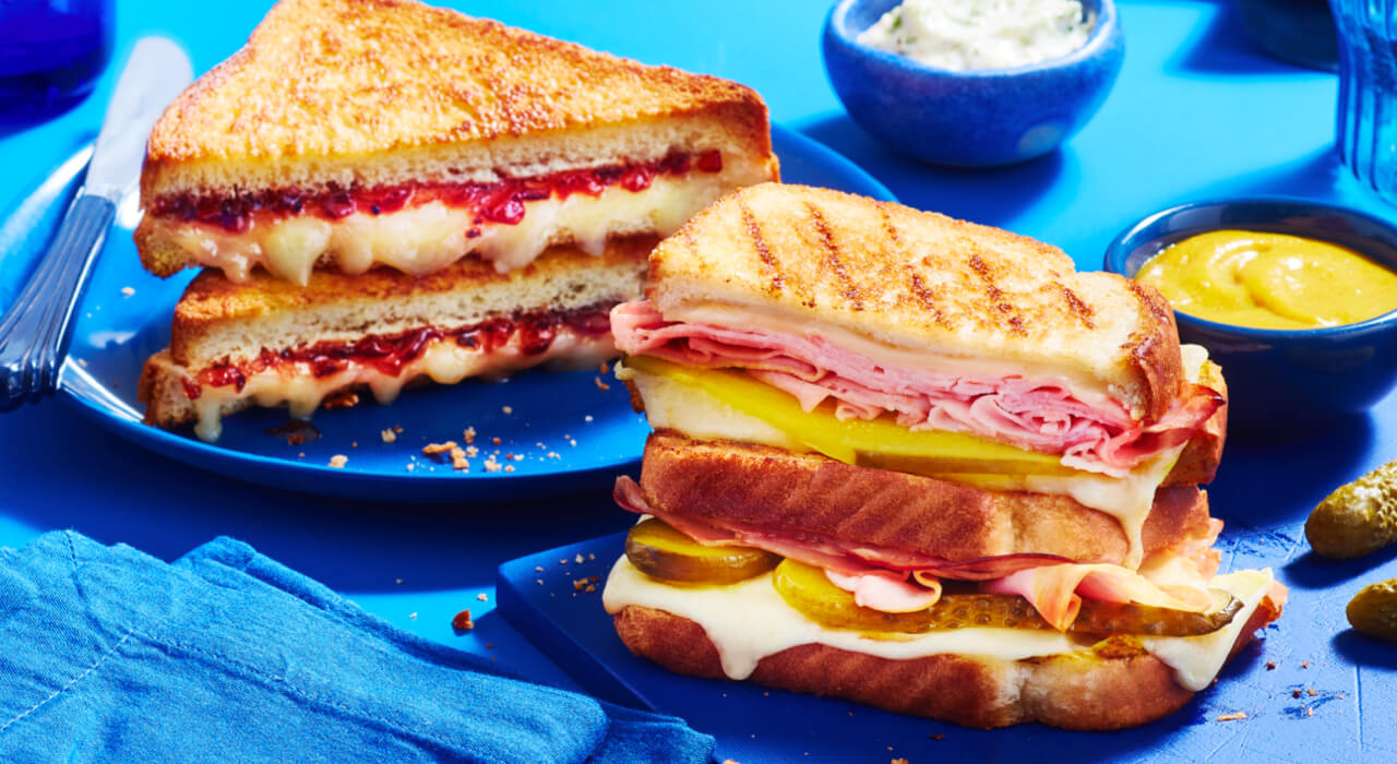A flavourful sandwich stuffed with bacon and cheese, along with a dip on the side.