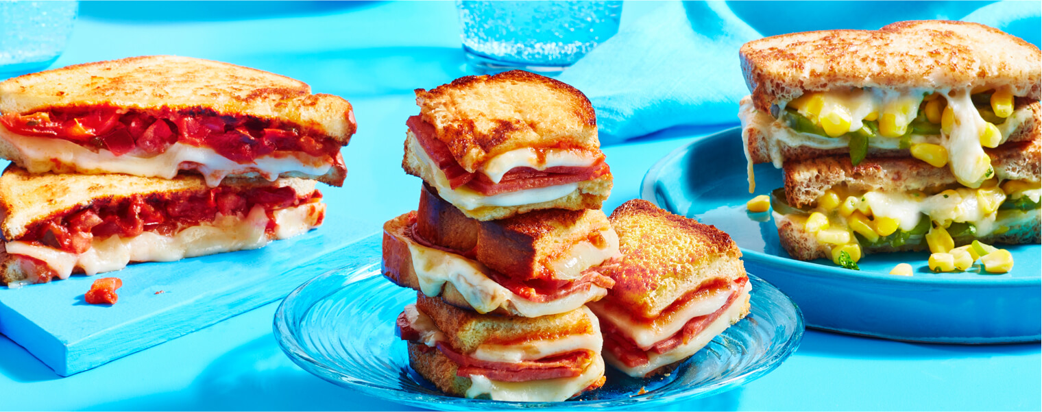 Salsa grilled cheese sandwich, pizza grilled cheese sandwich, ad corn-herb grilled cheese sandwich on blue plates