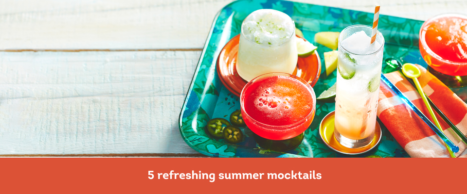 white wooden picnic table surface with aqua tray holding four colourful mocktails