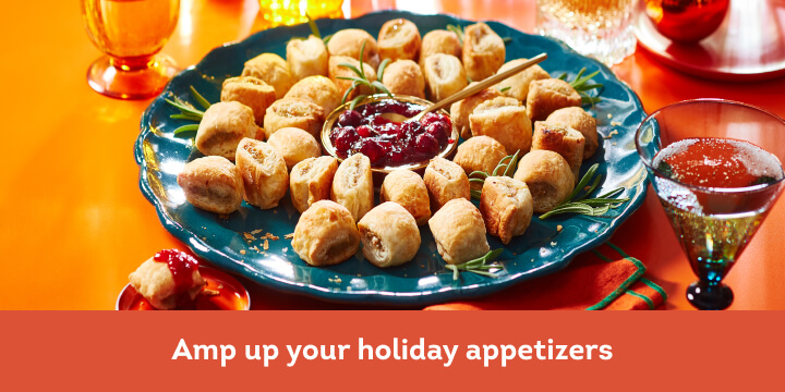 Blue platter filled with sausage rolls and cranberry dip