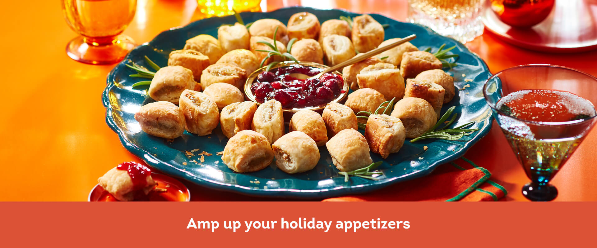 Blue platter filled with sausage rolls and cranberry dip