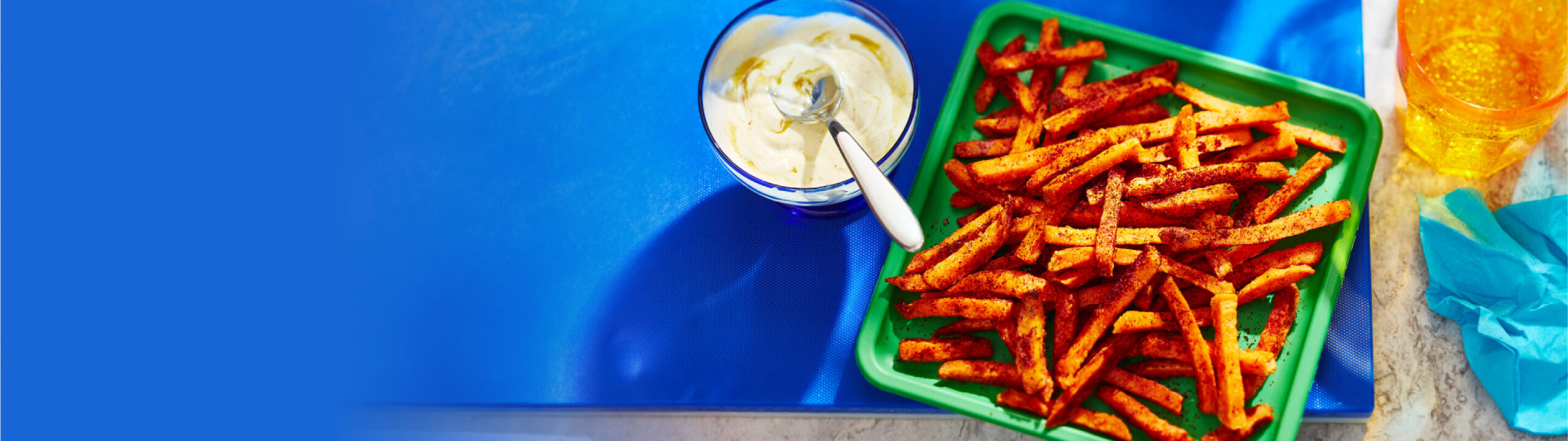 Sweet potato fries on a green plate with a side of extra spicy dip in a bowl.