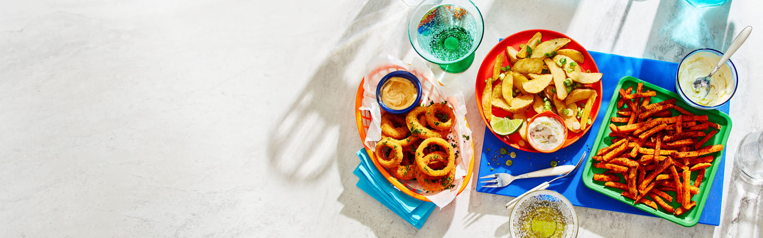 Sweet potato fries, Mexican-inspired fries and onion rings on a white backdrop