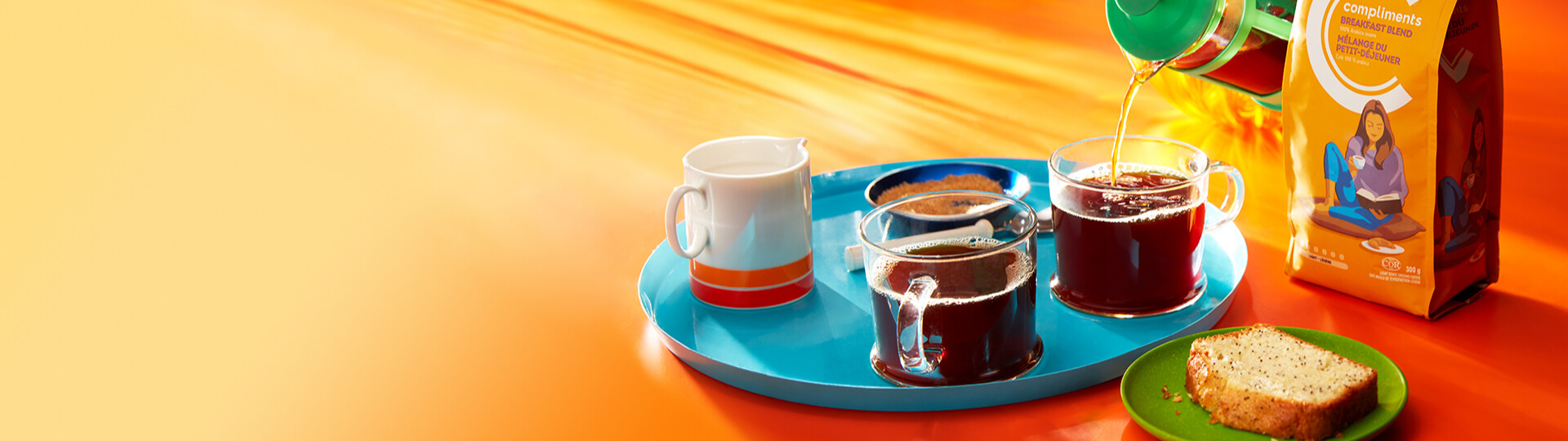 Coffee brewed and being poured into a mug beside a bag of Compliments coffee