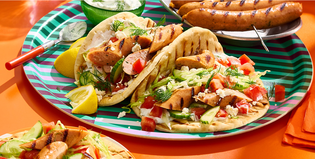 Three grilled sausage souvlaki and a skewer of grilled chicken sausage on an orange background.