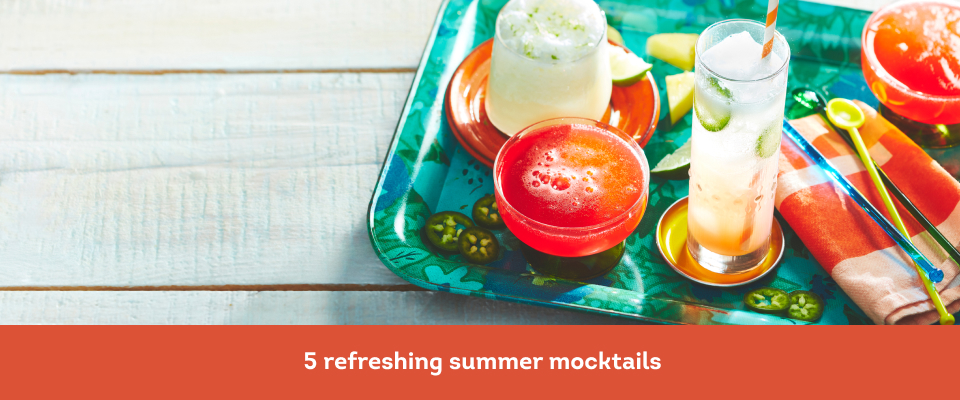 white wooden picnic table surface with aqua tray holding four colourful mocktails