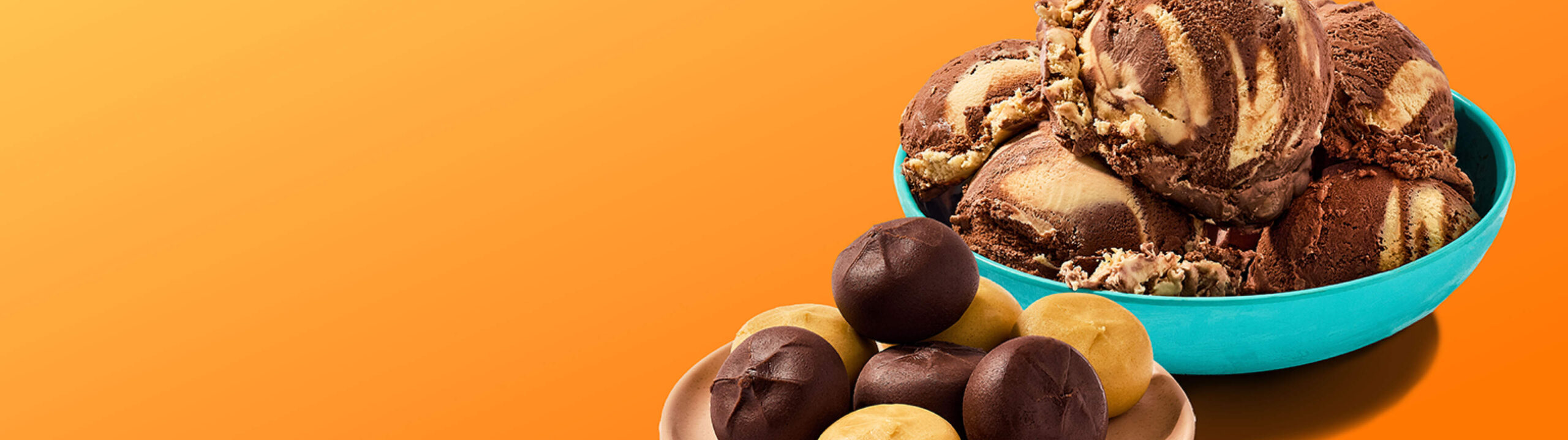 Scoop of peanut butter chocolate ice cream in a bowl and dough’chi bites beside it, on an orange background.