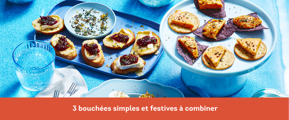 Boule de fromage et croustilles sur un support à gâteau blanc, brie aux canneberges sur un plateau de service bleu et œufs farcis au fromage sur une assiette bleue.