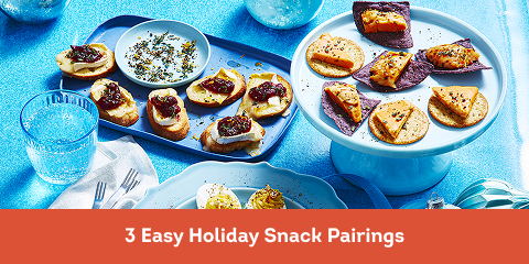 Cheese ball 'n' chips on a white cake stand, brie 'n' cranberries on a blue serving tray and devilled eggs 'n' cheese on a blue plate.